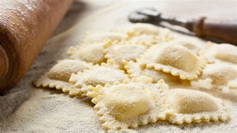 Proceso de armado de ravioles caseros, colocando el relleno y cubriendo con otra capa de masa.