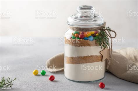 Frasco de vidrio con capas de ingredientes secos para cupcakes de chocolate y una cuchara de madera