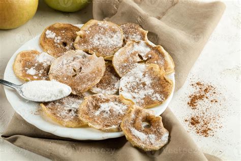 Fotografía detallada de Æbleskiver recién hechos, espolvoreados con azúcar glas y acompañados de mermelada roja.