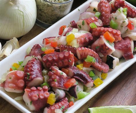 Plato de ensalada de pulpo fresco decorado con hojas de albahaca y aceite de oliva