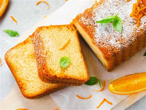 Bizcocho de naranja y cardamomo recién horneado y cortado en porciones, con un café al lado.