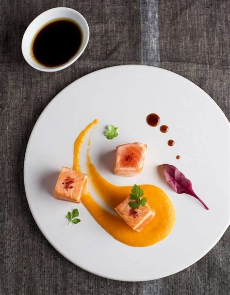 Salmón confitado con merkén emplatado con puré de porotos y pebre