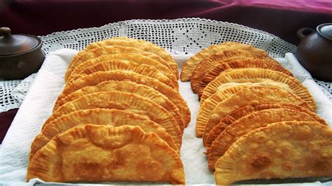 Empanadas chilenas recién fritas en una bandeja, con un fondo de celebración chilena