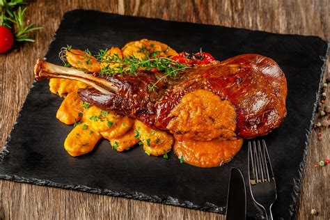 Plato de cordero a la parrilla con una porción de dulce de membrillo al lado