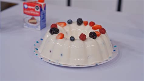Ilustración de una gelatina de tres leches con frambuesas y frutos rojos esparcidos.