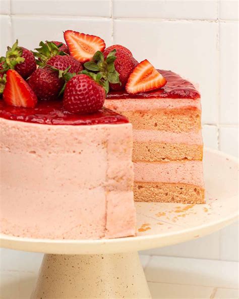 Fotografía profesional de una torta helada de frutilla con capas visibles y decoración de frutas frescas en la parte superior