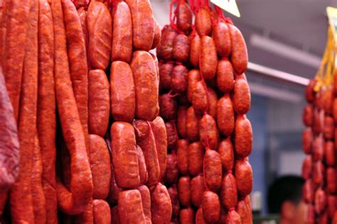 Variedad de embutidos (chorizo, butifarra, prieta, chistorra, longaniza, salchichas) listos para asar en una parrilla.