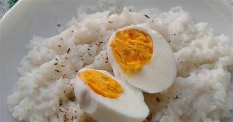Fotografía de un plato de arroz blanco esponjoso servido con huevo duro cortado en gajos y decorado con hierbas frescas
