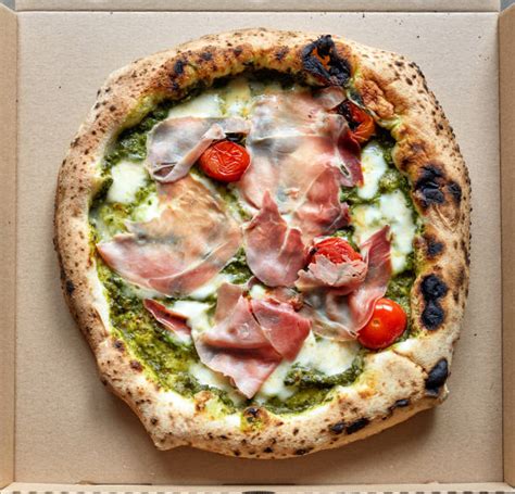 Fotografía gastronómica de una pizza artesanal recién horneada servida en un entorno montañoso de El Manzano