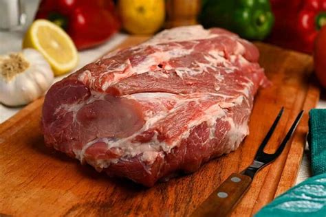 Fotografía gastronómica de una bondiola cruda marinada con hierbas frescas y especias.