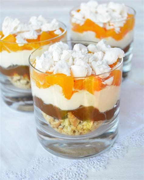 Vasitos individuales de postre con capas de mango brillante y crema blanca, decorados con hojas de menta.