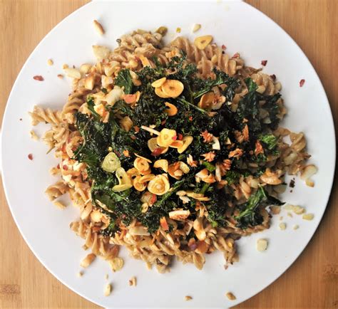 Plato de pasta con kale, ajo y limón en un entorno de cocina.