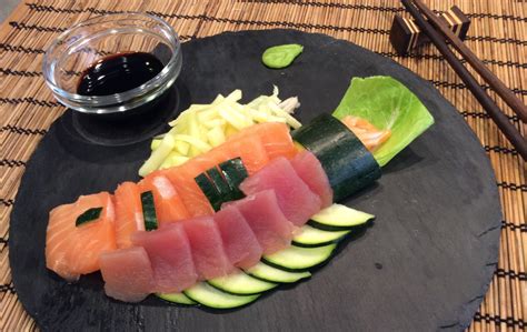 Plato de sashimi variado con cortes de salmón, atún y pulpo, decorado con jengibre y wasabi.