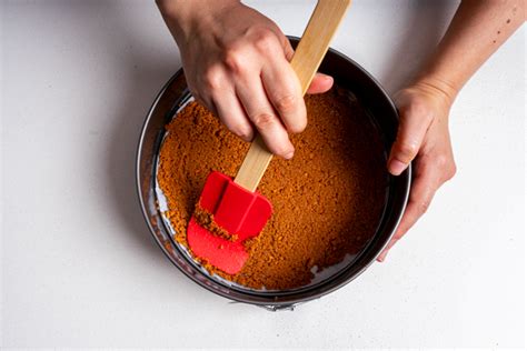 Foto de la base de galleta y nueces siendo aplastada en el molde.