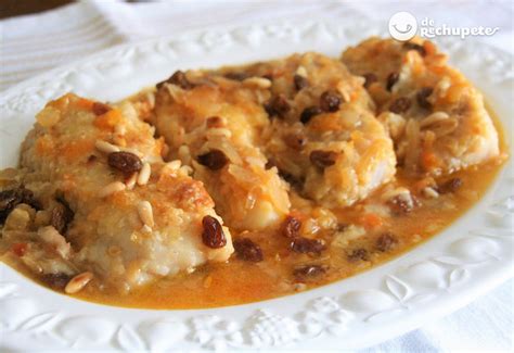 Fotografía de un plato terminado de bacalao a la miel, decorado con pasas y piñones.