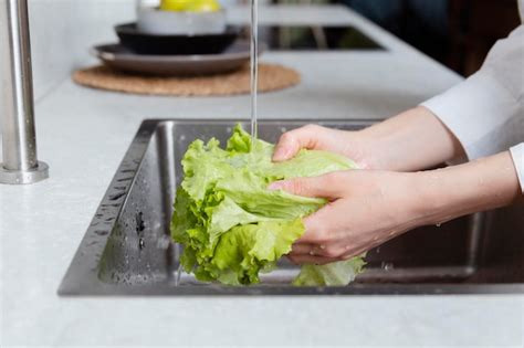Foto de una persona lavando lechuga bajo el grifo