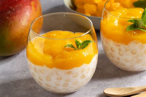 Imagen de un postre de tapioca servido en copas, decorado con ralladura de naranja o coco rallado.