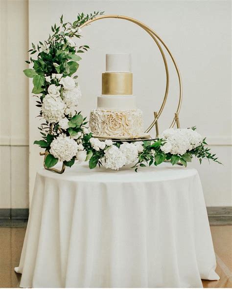 Mesa de pastel de bodas decorada con abundantes arreglos florales estacionales