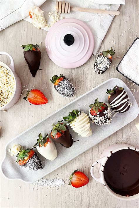Fotografía de fresas cubiertas de chocolate con diferentes toppings como sprinkles y virutas de chocolate.