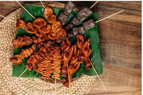 Fotografía macro de diversos platos de comida callejera filipina servidos en palillos de madera