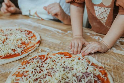 Niños decorando sus propias pizzas con ingredientes coloridos