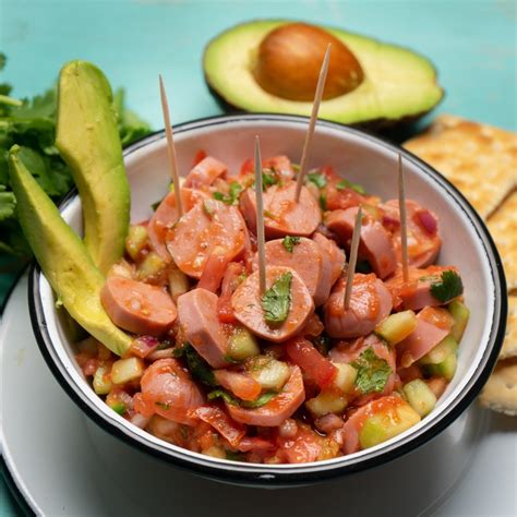 Cóctel picante de salchicha servido con galletas y aguacate