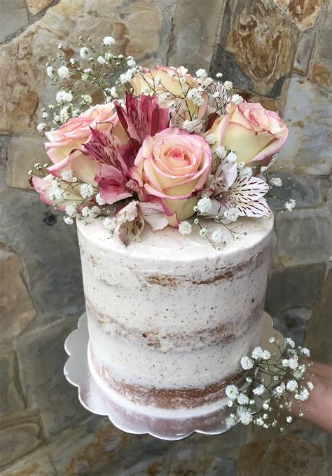 Fotografía profesional de una torta decorada con flores comestibles naturales y pétalos frescos
