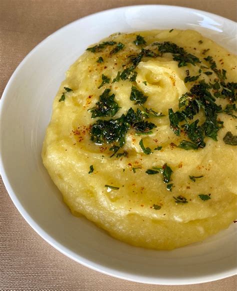 Fotografía de un bol con puré de yuca cremoso y suave, decorado con perejil fresco y un toque de aceite de oliva.