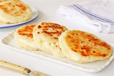 Arepas blancas tradicionales apiladas en una cesta, con algunos rellenos al lado