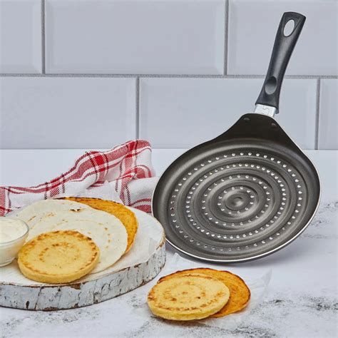 Diferentes utensilios de cocina para arepas: budare, sartén antiadherente, tostador
