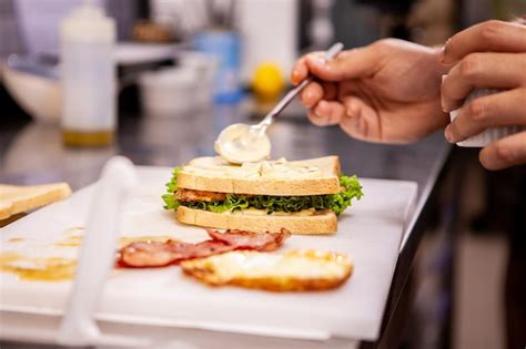 Fotografía de un chef preparando un sándwich gourmet con ingredientes frescos.