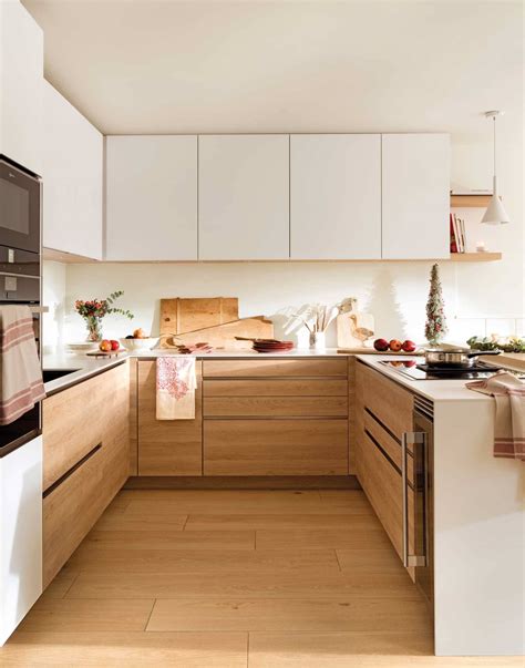 Cocina minimalista con muebles blancos y detalles en madera natural, destacando la luz.