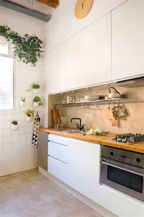 Cocina pequeña y funcional con acabados blancos y madera clara para maximizar el espacio.