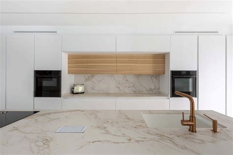 Cocina blanca y madera con una isla central multifuncional.