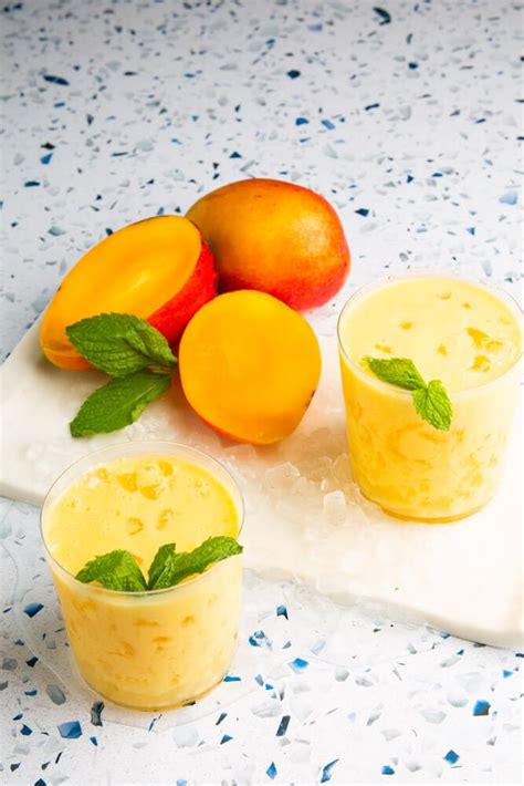 Ingredientes variados para lassi de mango dispuestos en una superficie limpia: mangos, yogur, leche, especias.