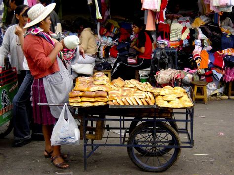 Fotografía antigua de mujeres vendedoras de comida callejera en La Paz, vestidas con polleras tradicionales.