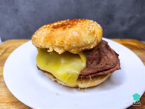 Fotografía profesional de un sándwich Barros Luco con queso derretido chorreando sobre carne de vacuno a la plancha