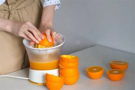 Persona exprimiendo naranjas manualmente en la cocina