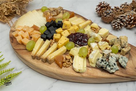 Variedad de quesos, galletas y acompañamientos en una tabla de madera