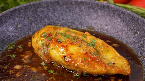 Pechugas de pollo rellenas horneándose en una bandeja con vino y caldo