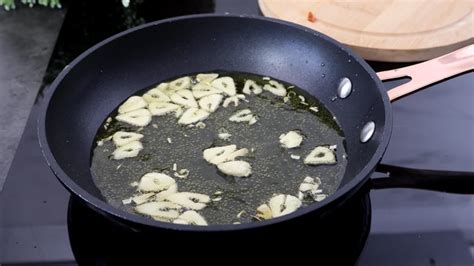 Ajos dorándose en una sartén y espinacas salteándose en el mismo aceite