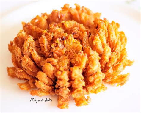 Foto de una flor de cebolla frita abierta y dorada en un plato con salsa