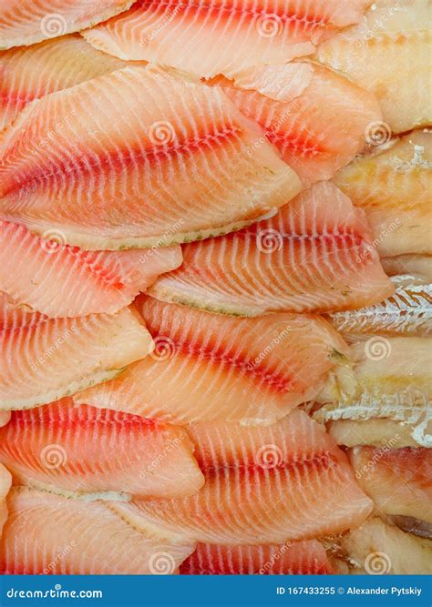 Fotografía de filetes de tilapia frescos en un mostrador de supermercado, mostrando su color y textura.
