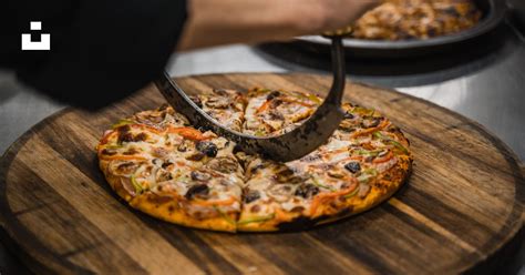 Foto de una persona cortando una pizza con un cortador de rueda