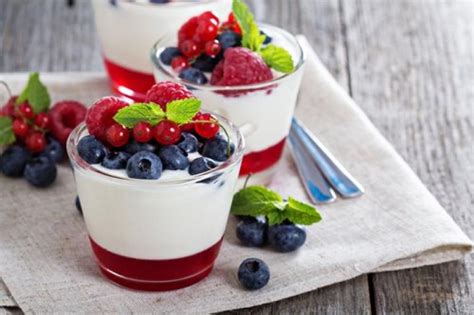 Vasitos con mousse de yogur y capas de mermelada, decorados con frutas frescas.