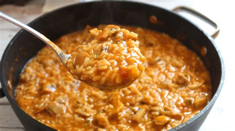 Imagen de arroz meloso con cerdo y setas cocinado en una cazuela de hierro sobre brasas