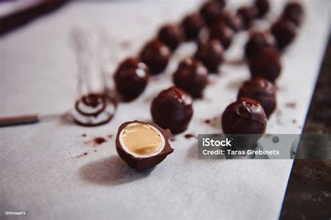 primer plano de bombones redondos cortados por la mitad mostrando un relleno fluido de caramelo y trozos de frutos secos