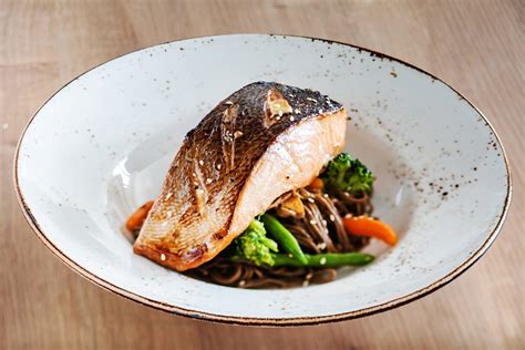 Plato de lomo de salmón con piel crujiente y verduras salteadas