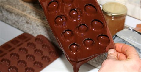 Niño ayudando a rellenar moldes de bombones con chocolate