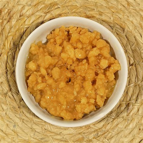 Foto detallada de la textura del dulce de leche cortada, mostrando los grumos en almíbar dorado.